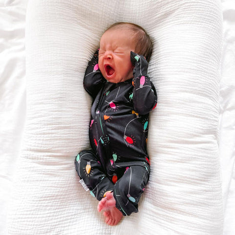 Newborn wearing a printed Dreamiere zip sleeper