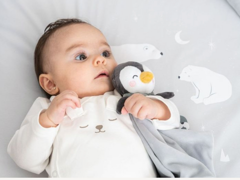 Baby holding a soft Saro penguin toy