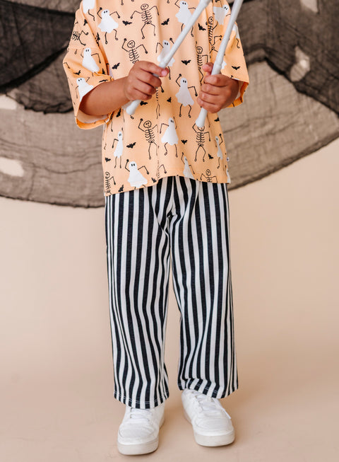 Child wearing a patterned shirt and striped pants on a beige background