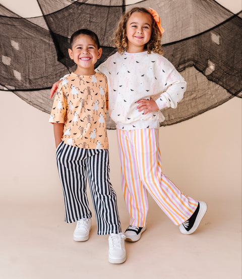 Two children standing together in front of a decorative net on a beige background