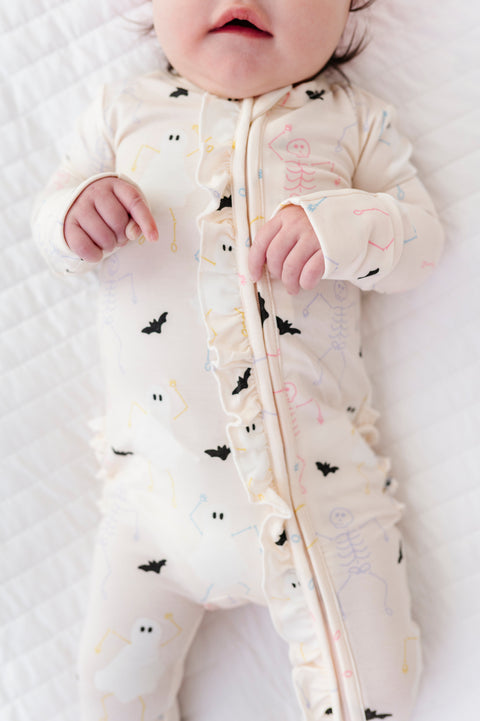Baby wearing a cream onesie with black animal prints on a white background