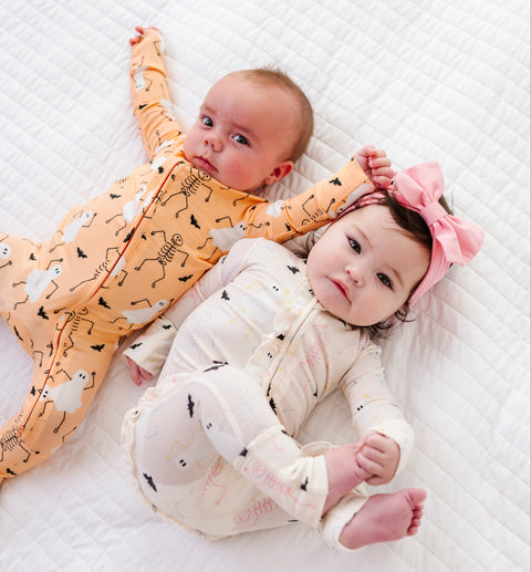 Two babies in pajamas lying on a textured white surface
