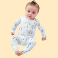 Baby wearing a white onesie with rainbow patterns on a light blue background