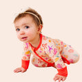 Baby in a colorful outfit crawling on a beige background