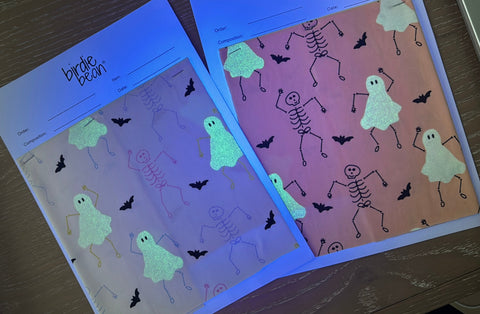 Two sheets of paper with Halloween-themed designs on a wooden surface.