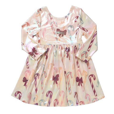 A long-sleeve children's dress with a shiny, iridescent finish, featuring an all-over candy cane print with bows in pink, purple, green, and orange on a pale cream background.